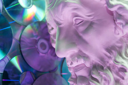 Antique statue of Homer head close up on a glitter CDs background. Concept of music, style, vintage.