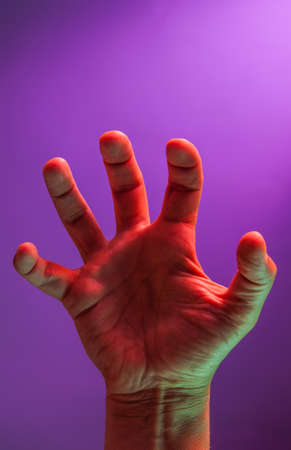 Bright fluorescent colorful hands isolated on a dark background. Close-up.