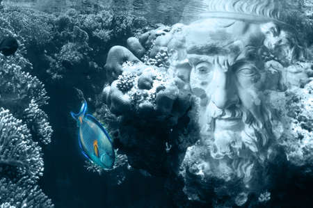 Face of ancient statue on a underwater background with corals and fish. Art, adventure, underwater archeology concept.の写真素材