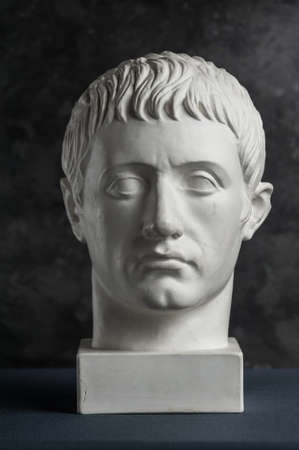 Gypsum copy of ancient statue Germanicus head on dark textured background. Plaster sculpture man face.の写真素材