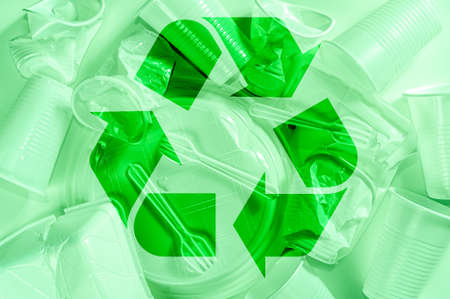 Disposable plastic tableware and recycling sign on a light background in green colors. Minimalistic ecologically clean still life. Pop Art. And ecology problem concept.の写真素材