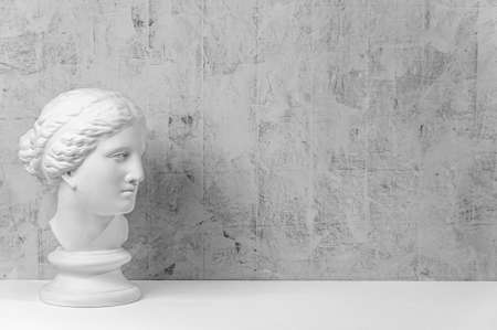 Mockup with ancient white statue of bust of Venus with grey textured background .Plaster sculpture woman face. The goddess of love in Greek mythology. Renaissance epoch. Copy space.の写真素材