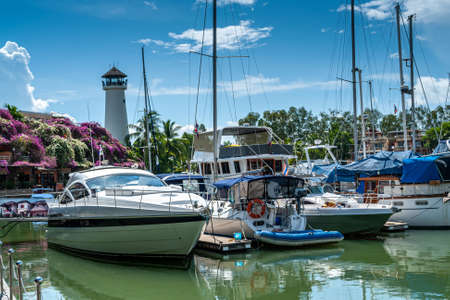 Moored sailboats against the blue sky with clouds in the afternoon. Lighthouse surrounded by palm trees. House in flowers. Thailand. Yachts.の写真素材