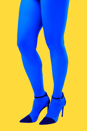 Close-up picture of womans beautiful blue legs in high heels shoes on acid yellow color background. Disco lights. Fasion. Surreal art. Funny modern art collage. Pop art. Zine culture. Side view.の写真素材