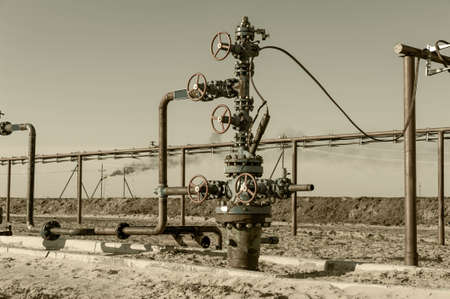Petroleum well wellhead equipment. Hand valve with handwheel on the flow line. Oilfield site. Oil, gas industry concept. Industrial site background. Production oil. Multiple check valve gate armature.の写真素材