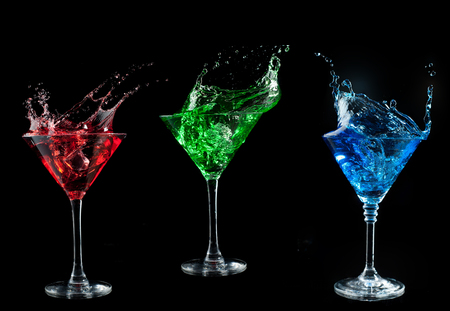 blue cocktail splashing into glass on black の写真素材