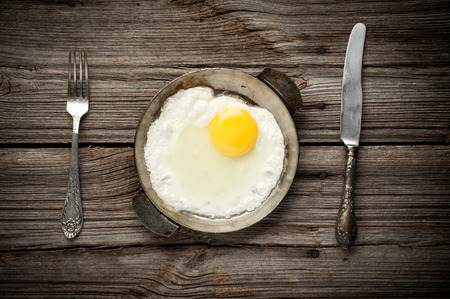 Fried egg on a pan served on wooden background の写真素材