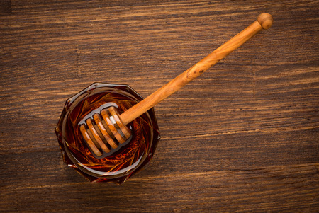 Fresh natural honey in a jar with honey spoon on a wooden rustic vintage tableの写真素材