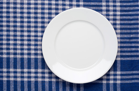 White classic plate on blue checkered tablecloth. Top View.の写真素材