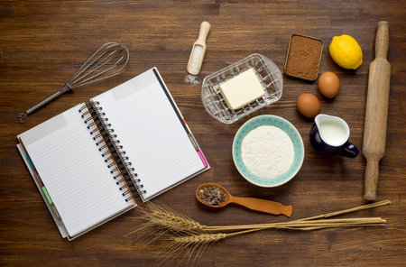 Baking cake in rural kitchen - dough recipe ingredients (eggs, flour, milk, butter, sugar) on vintage wooden table from above. Background layout with free text space.の写真素材