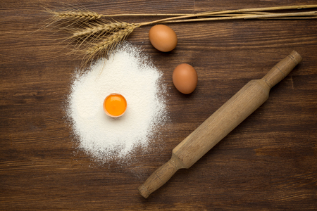 baking background with eggshell and rolling pin on wooden tableの写真素材