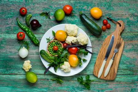Fresh Organic Vegetables on a White Plate with Knife and Fork.   Vertical Composition.の写真素材
