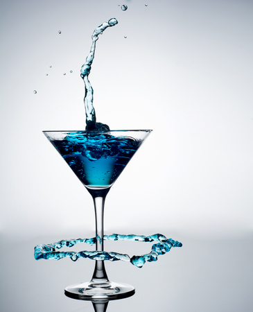 Blue cocktail with splash on white background.の写真素材