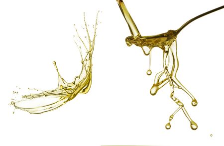 Pouring oil splash on spoon. Isolated on white background.の写真素材