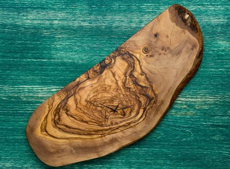 Olive wood cutting board on wooden background.の写真素材