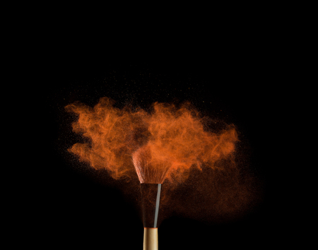 Makeup brushes on black background with colourful powder splash close up.の写真素材