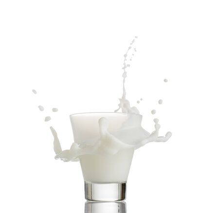 glass of splashing milk isolated on blue backgroundの写真素材