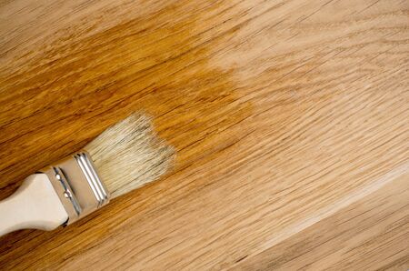 closeup hand use brush paint clear lacquer on wood surface.の写真素材