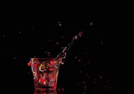 Bright cocktail in glass and splashing water on dark background.の写真素材