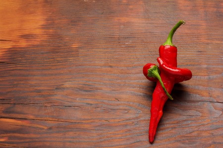 fresh red chilli on old wooden background .