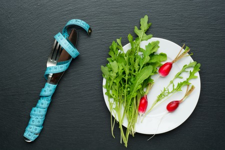 Fresh salad and measuring tape on stone backgroundの写真素材