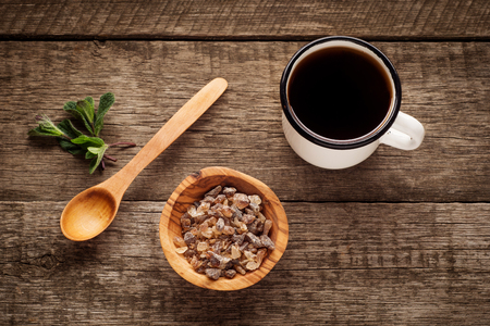 old enamel cup of tea with brown sugar mint and wooden spoon on vintage wooden background.の写真素材