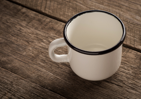 Old enamel empty cup on a wooden surface.の写真素材