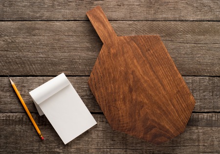 Chopping board and cookbook on wooden background with copy spaseの写真素材