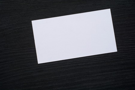 Photo of blank white business cards on a dark wooden background. Mock-up for branding identity.の写真素材