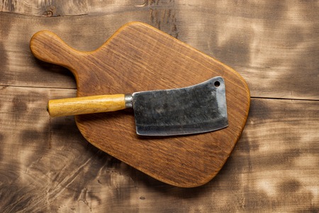 Butcher. Vintage butcher meat cleavers with chopping board on dark wooden background.の写真素材