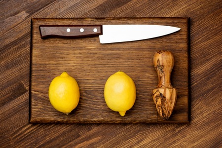 Fresh lemon and knife on wooden chopping boardの写真素材