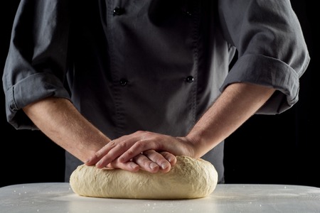 Male hands knead the dough for pizza or bread.