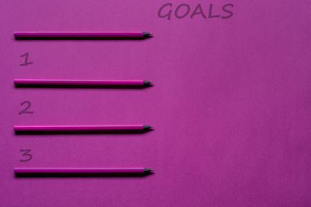 Top view goals list with pencils and copy space on pink paper background.の写真素材