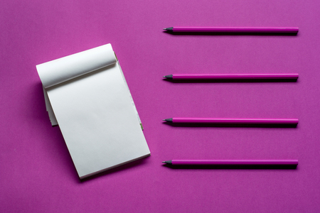Top view notepad with pencils and copy space on pink paper background.の写真素材