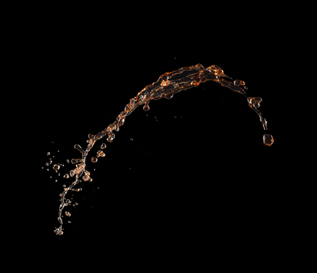 Isolated shot of whiskey splash isolated on black background.の写真素材