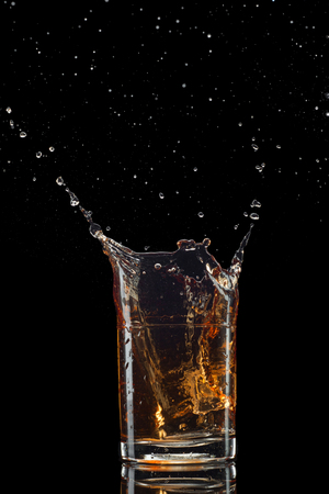 Isolated shot of whiskey with splash on black background.の写真素材