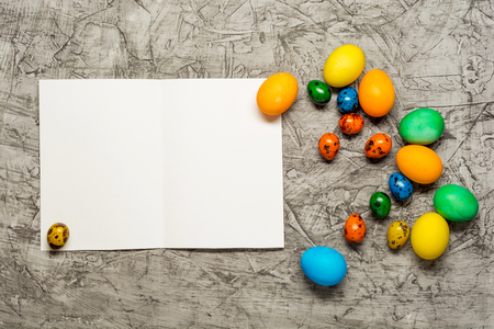 Colorful Easter eggs on concrete background with blank paper .の写真素材