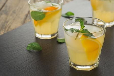 Cocktail. Orange juice with mint and ice rustic wooden tableの写真素材