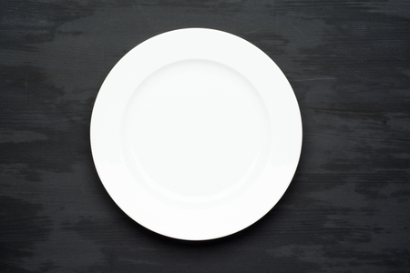 Empty plate on dark black wooden background. Top view with copy space.の写真素材