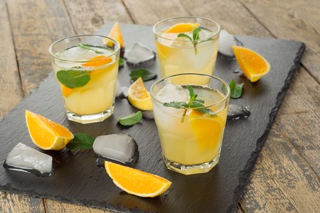 Cocktail. Orange juice with mint and ice on rustic wooden tableの写真素材
