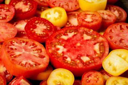Variety of ripe fresh organic gardening tomatoes different kind and colors with water spot and basil leaves in wood tray over old grey wooden background. Flat lay, spaceの写真素材