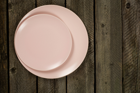 Empty pink plates over wooden table background. View from above with copy spaceの写真素材