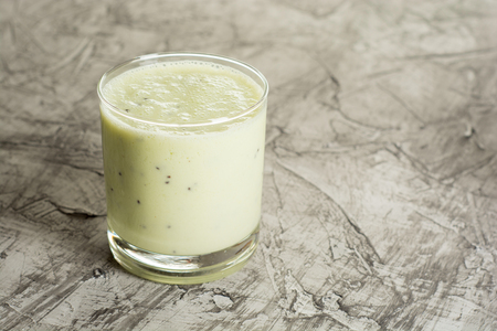 Fresh homemade yogurt in a glass with kiwi. On a concrete background. Dark backgroundの写真素材