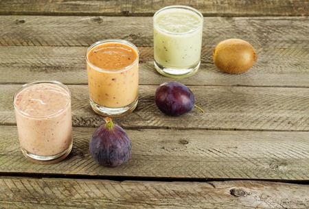 Three Fresh homemade yogurt in a glass with plum, kiwi and Fig. On a concrete background with copy space.の写真素材