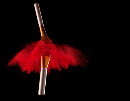 Makeup brush with red powder explosion on black backgroundの写真素材