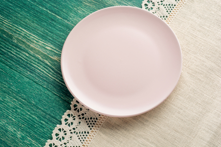 Empty pink plate on tablecloth on wooden table. Top view.の写真素材