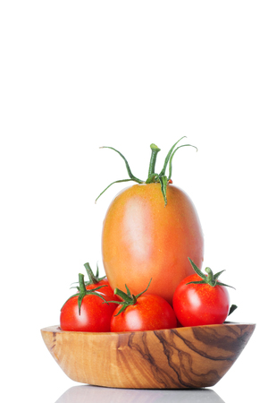 Fresh ripe tomatoes in wood bowl isolated on white background.の写真素材