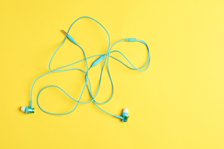 Flat lay concept: headphones on yellow backgrounds. Blue headphones on yellow background, top view, copyspace. Trendy colorful photo. Minimal style with colorful paper backdrop .の写真素材