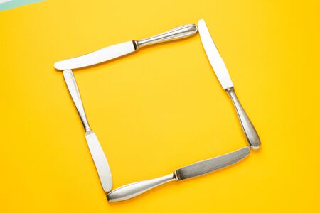 Creative layout frame made of decorative set of knifes on a yellow background. Flat lay. Food...