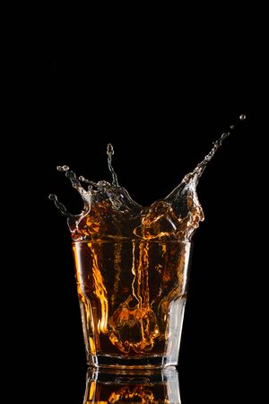 Glasses of whiskey with splash, isolated on black background.の写真素材